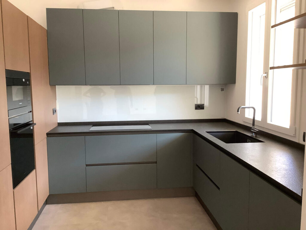 Ante in laminato cannettato, laminato verde comodoro, piano in granito nero assoluto fiammato e spazzolato, schienale magnetico in vetro con luce integrata